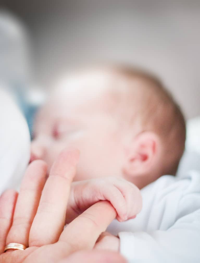 Ein Neugeborenes hält den Finger seiner Mutter