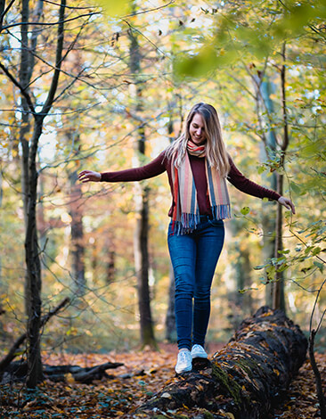 Endometriose Spezialistin Nicole Heinze balanciert auf einem umgefallenen Baum im Wald